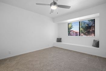 A room with a ceiling fan and a window with a view of a house.